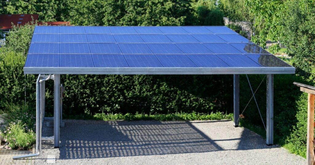 Un carport ouvert dont la toiture plate et inclinée est couverte de panneaux photovoltaïques. 